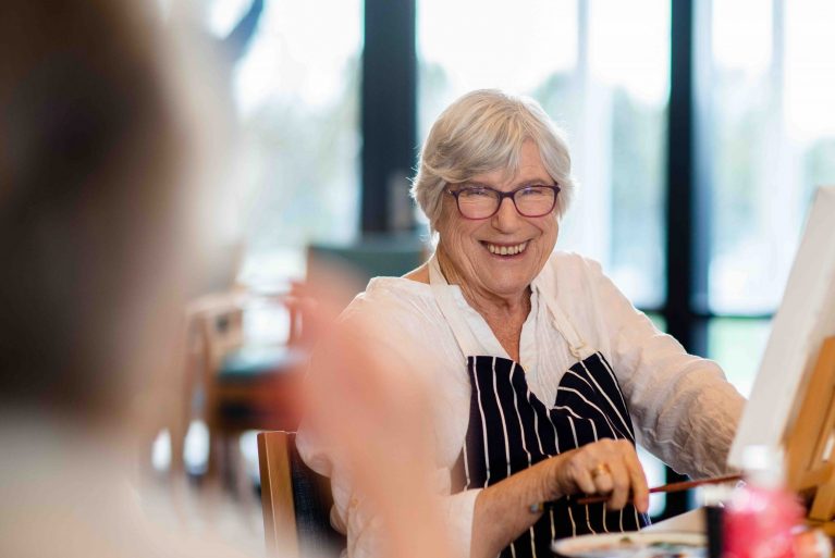 Older woman painting and smiling