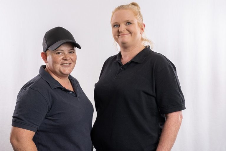 Two female service support officers smile at the camera.