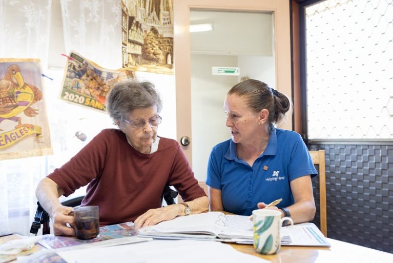 A home care coordinator talks with an older woman as they go through paperwork