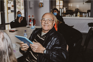 home care client David Willsher holds his Life Story book and smiles at the camera