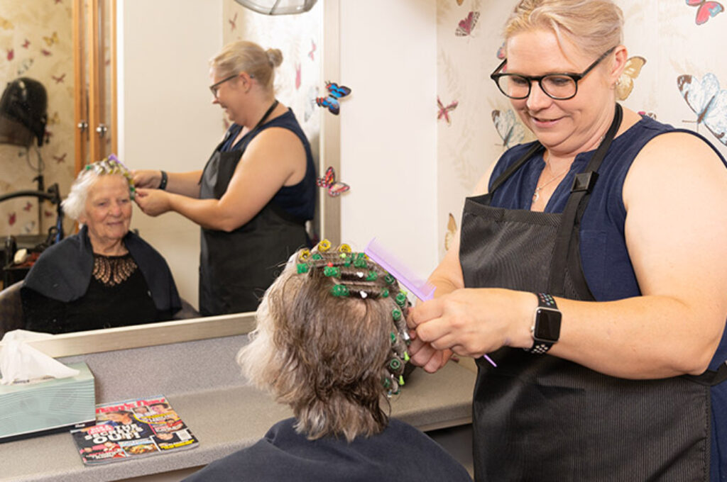 Hair dresser styling elderly woman's hair