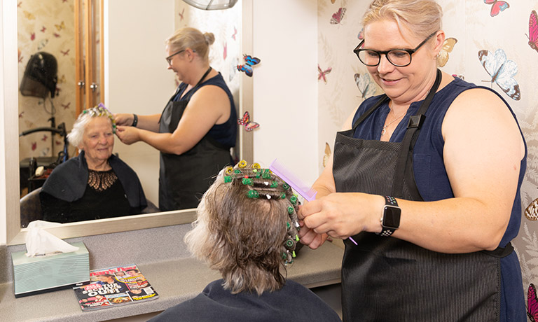Hair dresser styling elderly woman's hair