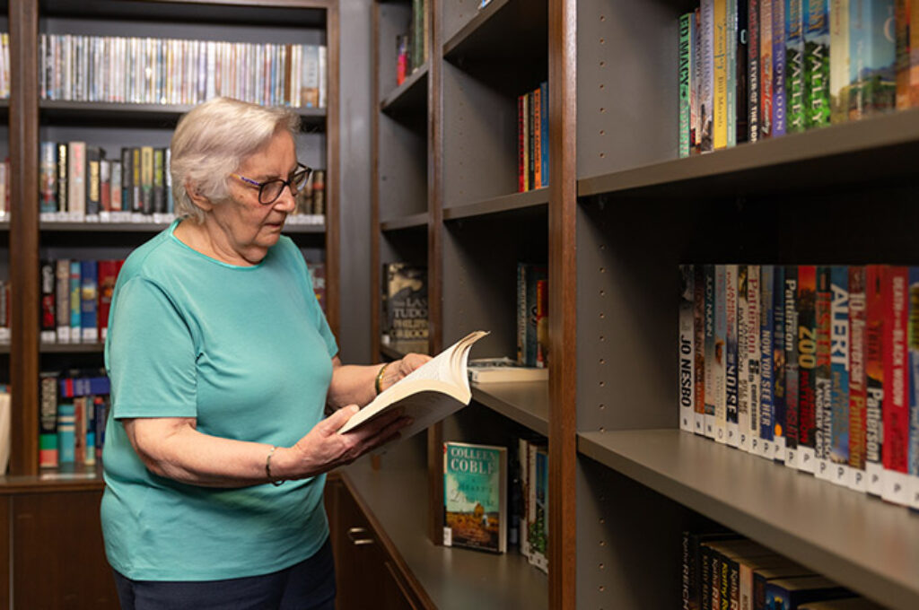 Elderly woman reading book in library