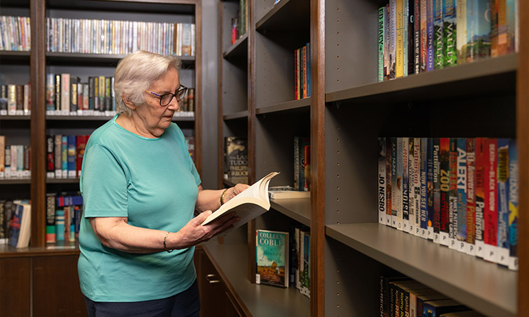 Elderly woman reading book in library