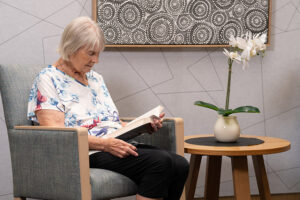 Edlerly woman sitting in armchair reading