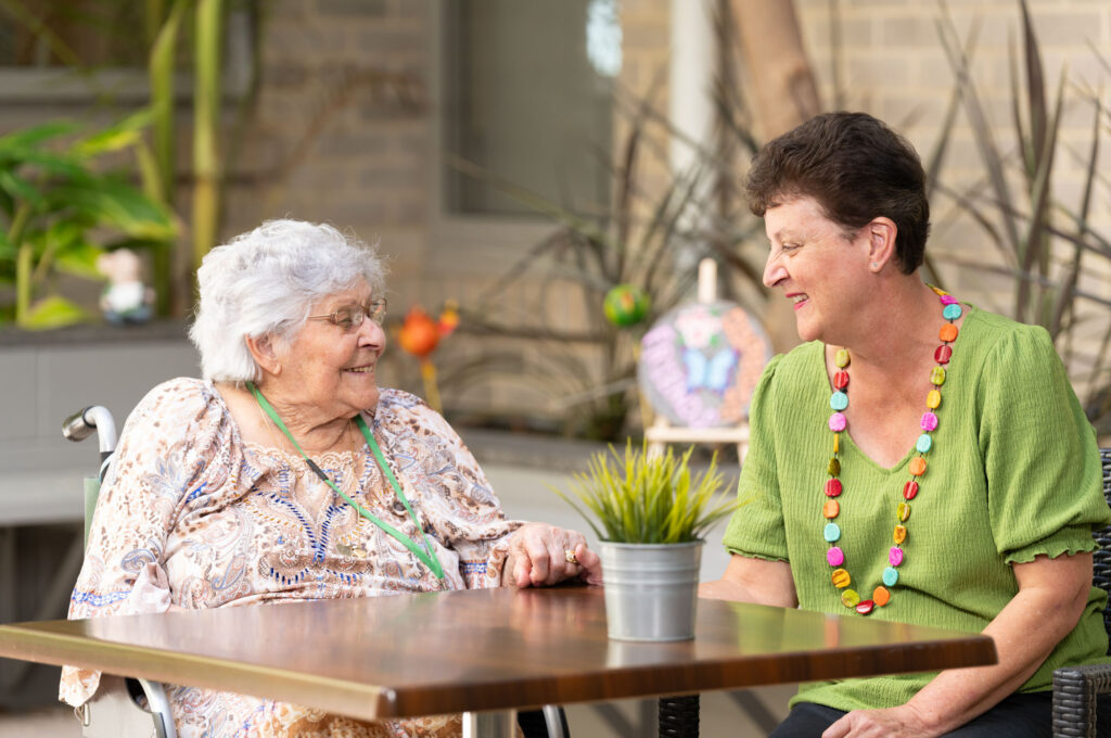 Two women talking to each other and smiling