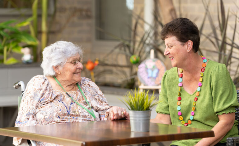 Two women talking to each other and smiling