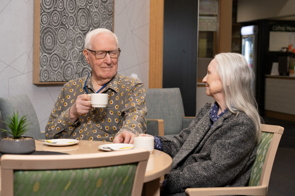 Elderly man and woman having cup of tea together